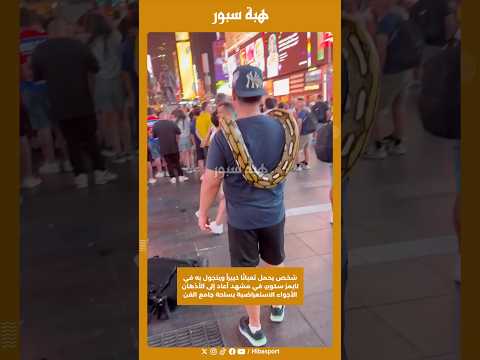 شخص يحمل ثعبانًا كبيراً ويتجول به في تايمز سكوير، في مشهد أعاد إلى الأذهان الأجواء الاستعراضية